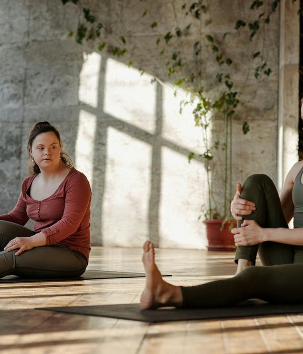 Woman in a peaceful yoga pose in a sunlit room.